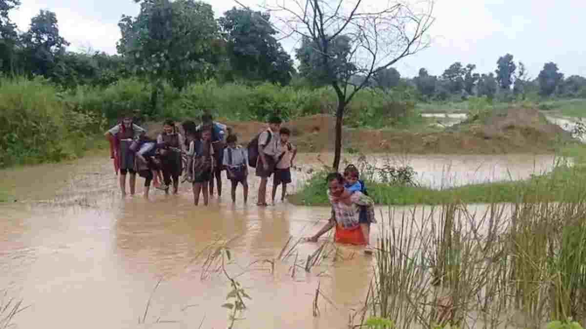 सूरजपुर में मजबूरी की तस्वीर: कंधे पर बच्चों को बैठाकर उफनता नाला पार करा रहा किसान, विकास के दावों पर उठे सवाल